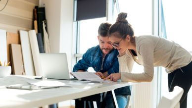 foto zeigt einen mann und eine frau die sich an einem beratungstisch über einen laptop beugen