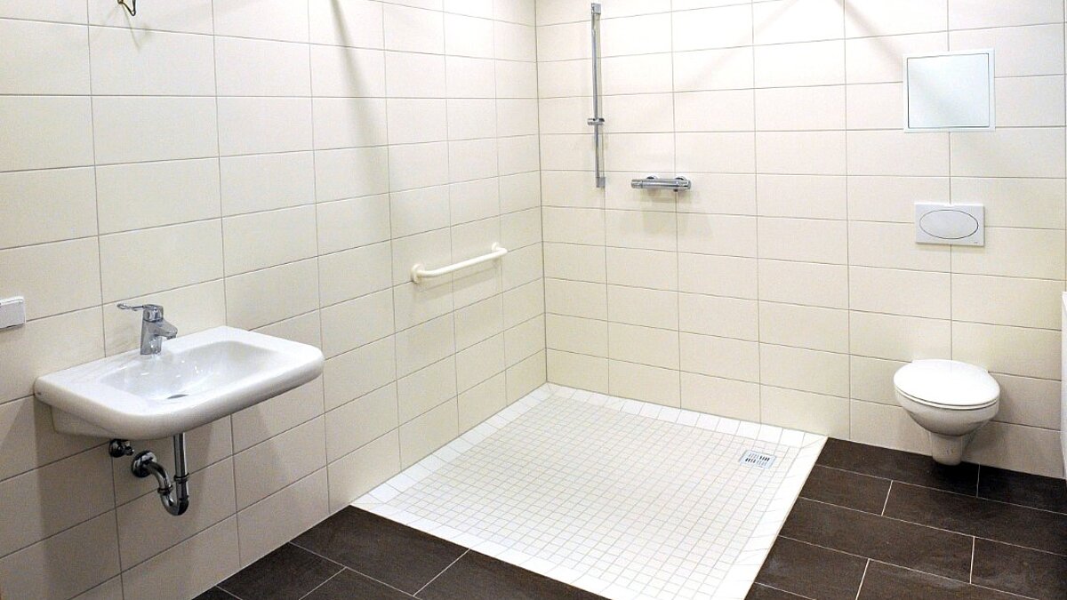 foto zeigt behindertengerechtes bad mit ebenerdiger rollstuhlgeeigneter dusche
