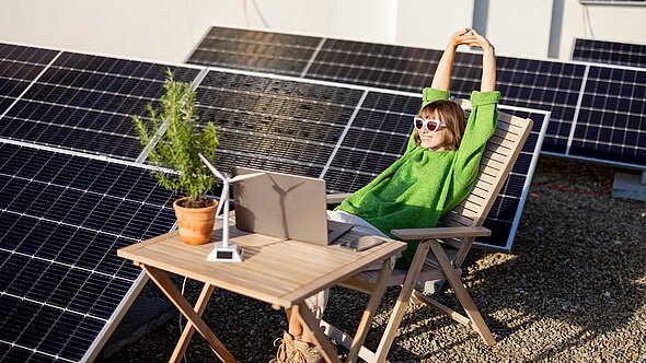foto zeigt eine frau auf einer sonnenliege neben einer pv-anlage