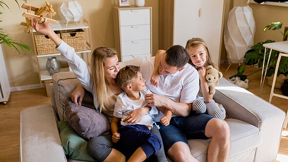foto zeigt mann frau und zwei kinder auf couch sitzend